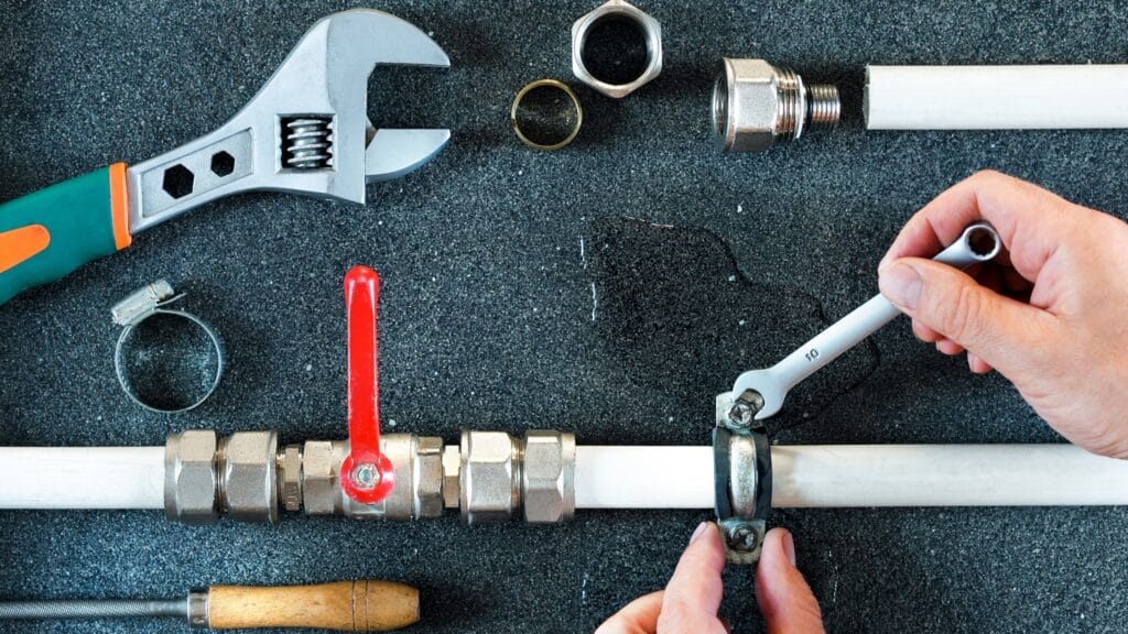 Plumber repairing a pipe valve with an adjustable wrench in Oregon City