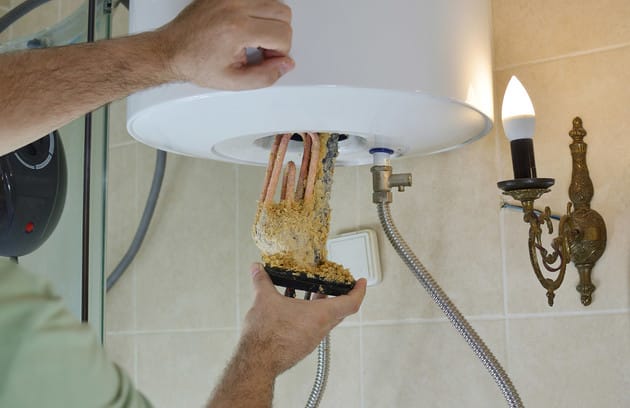 Technician removing mineral buildup from a water heater in Oregon City