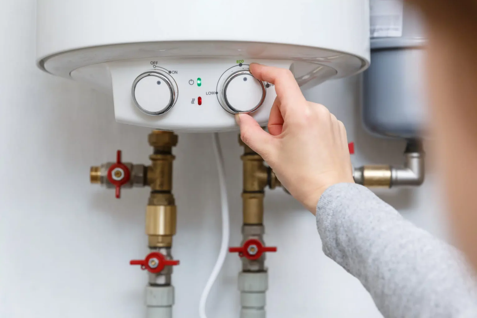 Homeowner adjusting the temperature controls on a water heater in Oregon City